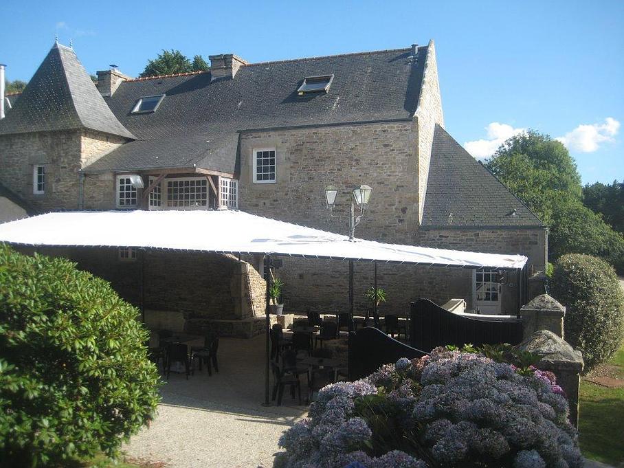 Terrasse avec chaises et tables sous une bâche