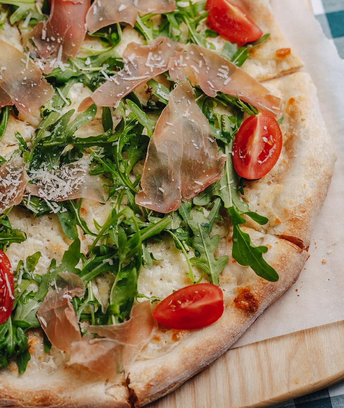 Pizza backt in einem Holzofen, mit glühenden orangefarbenen Ziegeln und Flammen in der Ecke