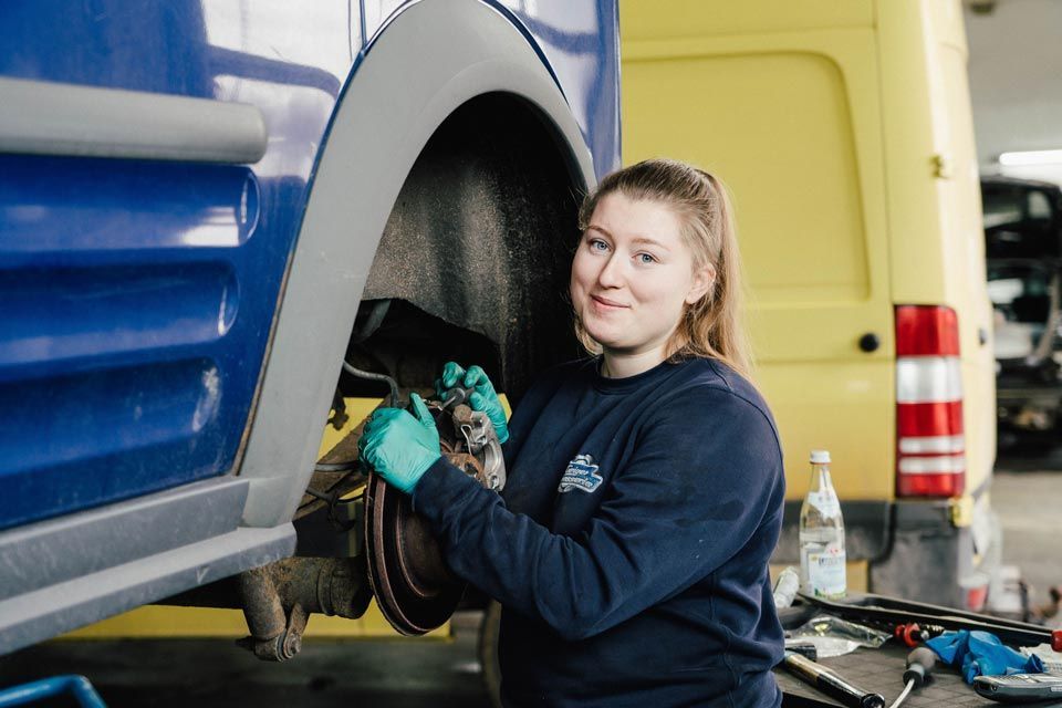 Eine Mitarbeiterin von Karosserie Geiger bereift ein Auto