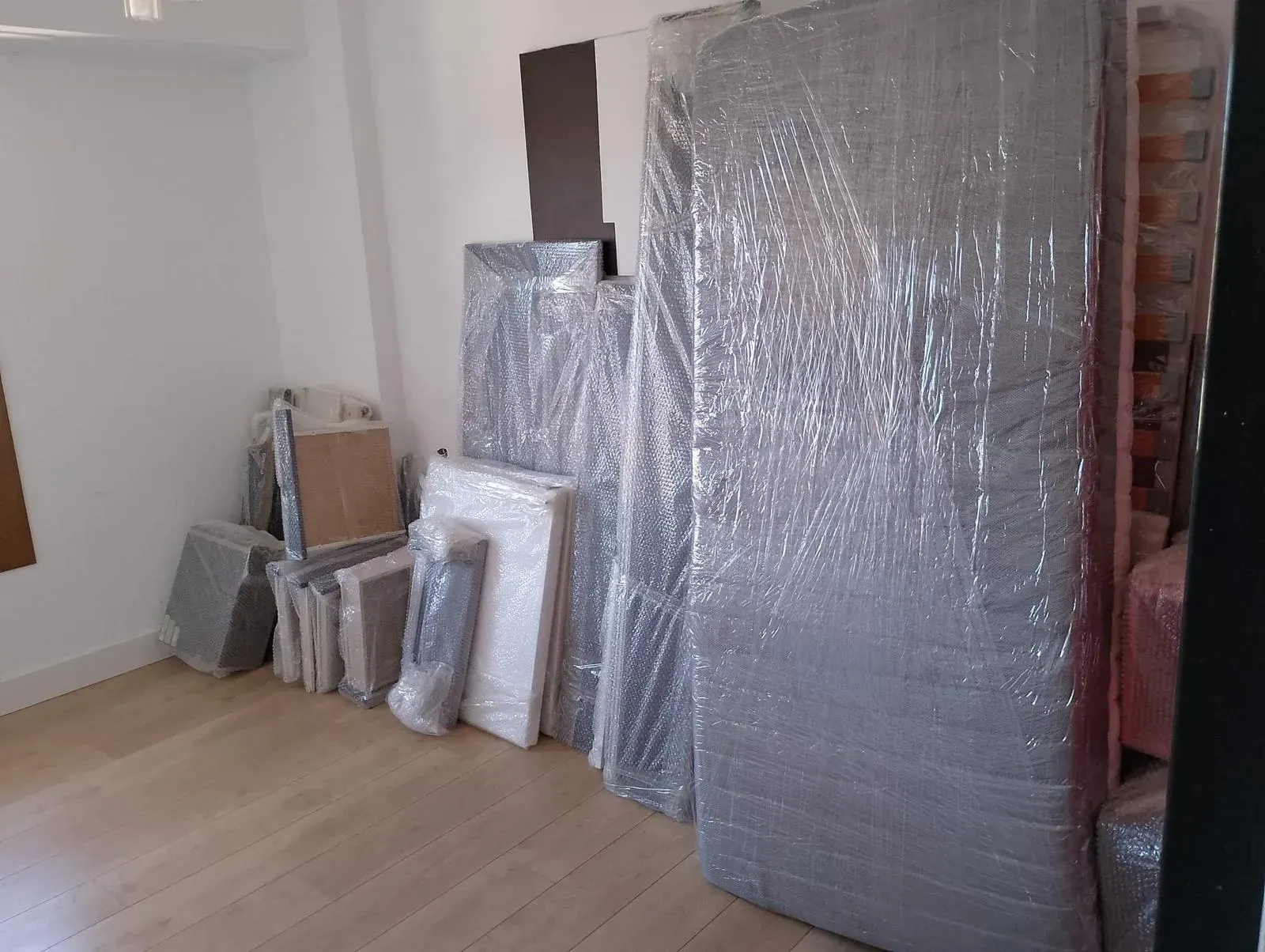 Una habitación llena de cajas y colchones envueltos en plástico.