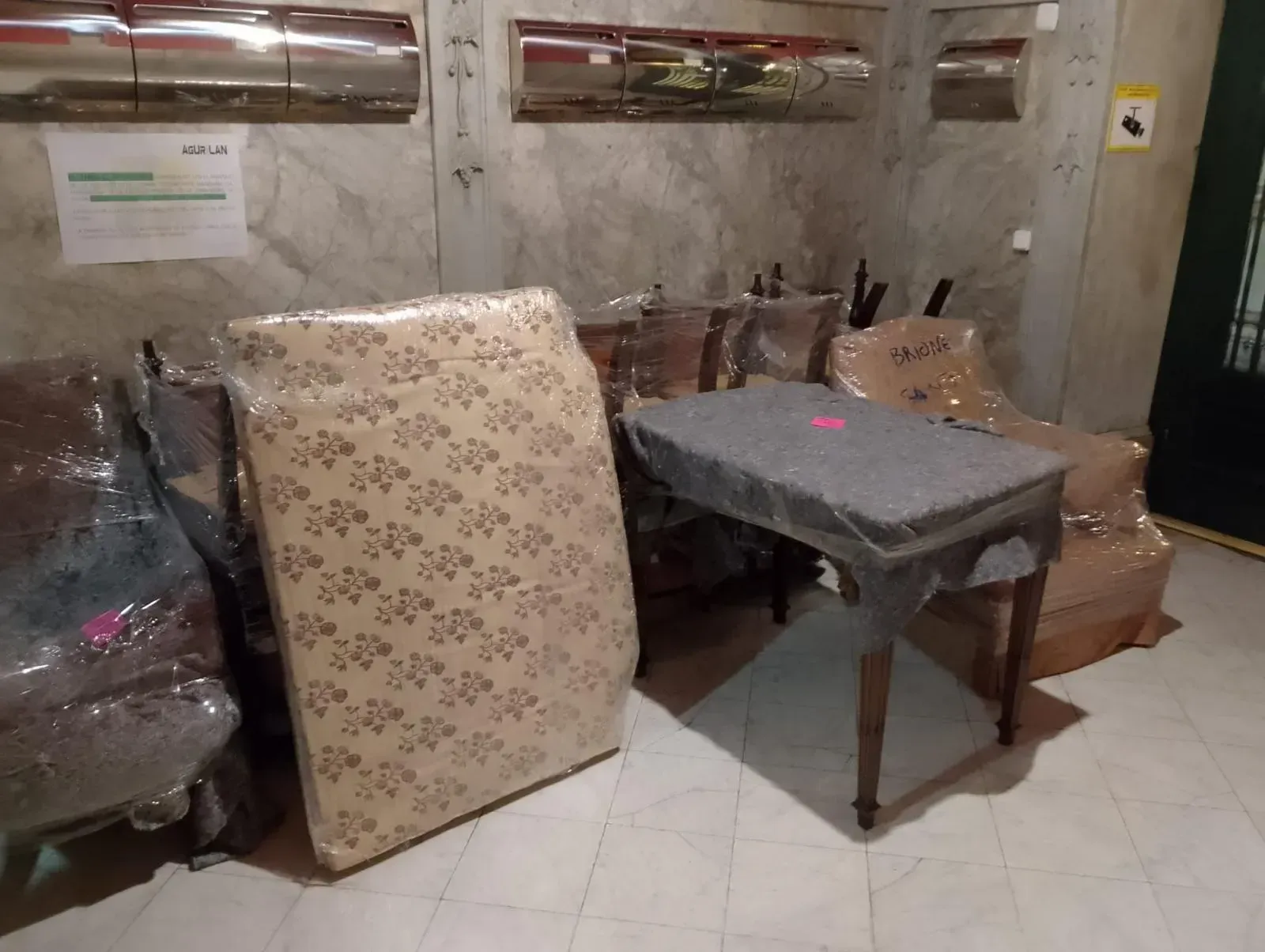 Una habitación llena de muebles y un colchón envuelto en plástico.