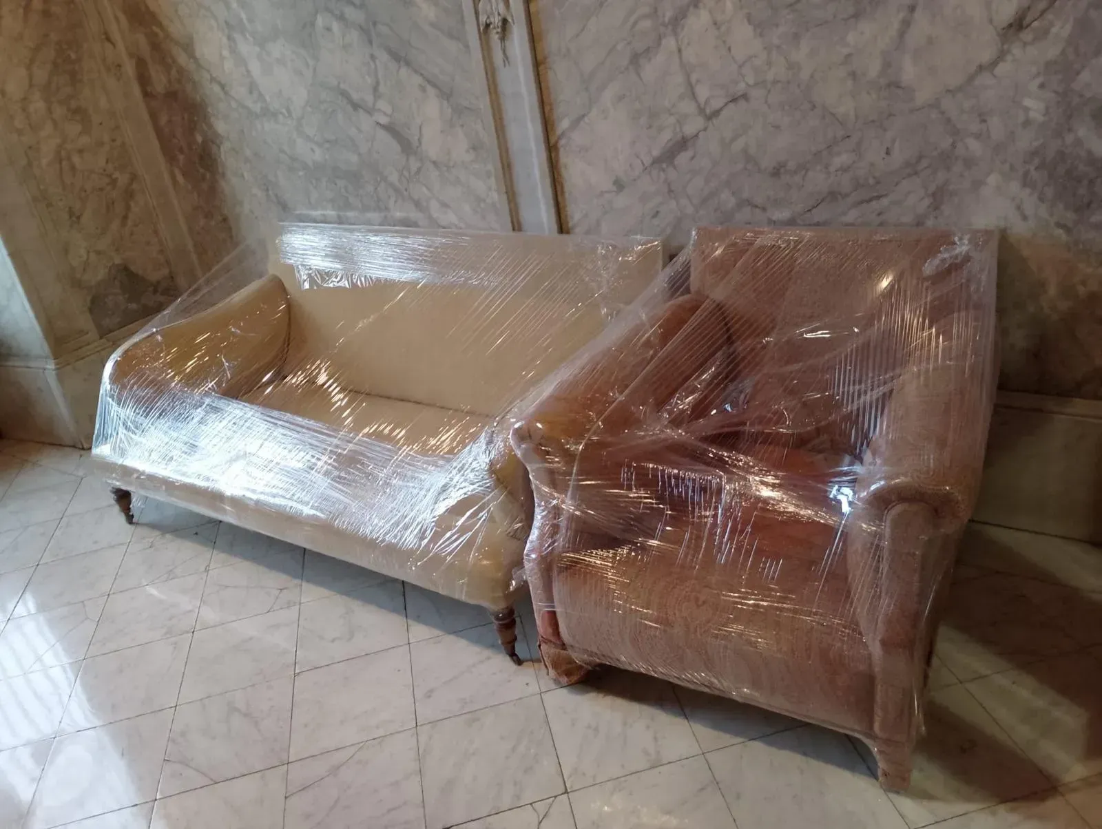 Un sofá y una silla envueltos en plástico en una habitación.