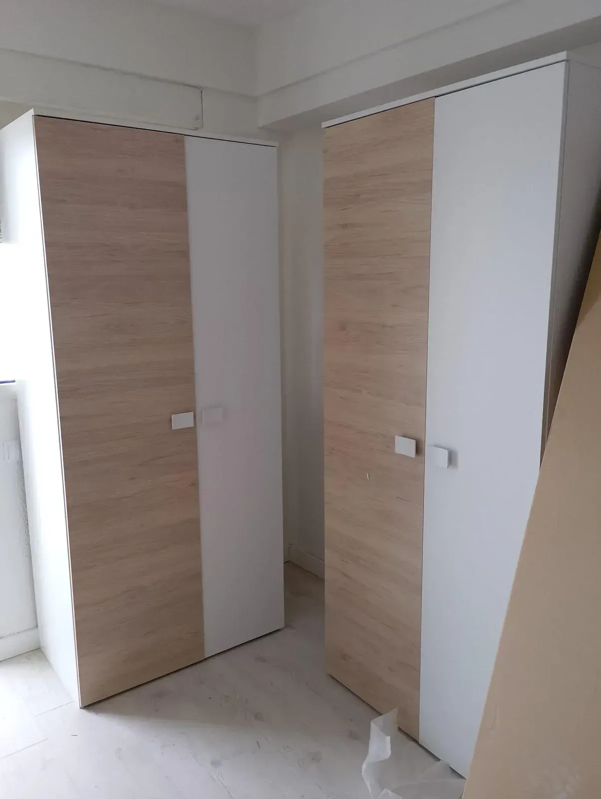 Dos armarios blancos y de madera están ubicados uno al lado del otro en una habitación.