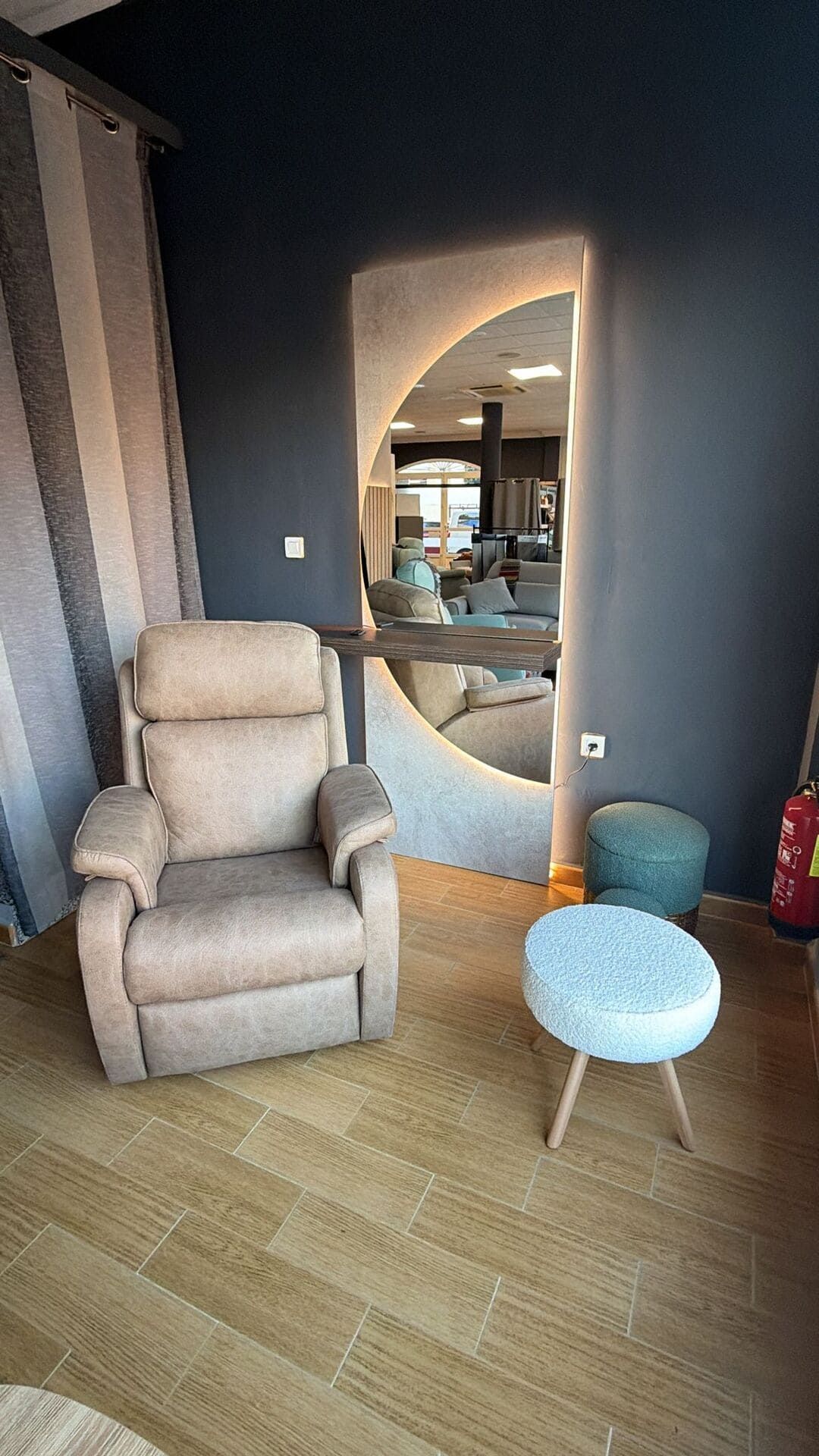 Sillón reclinable y otomana color beige junto a un gran espejo en una habitación con suelo de madera.