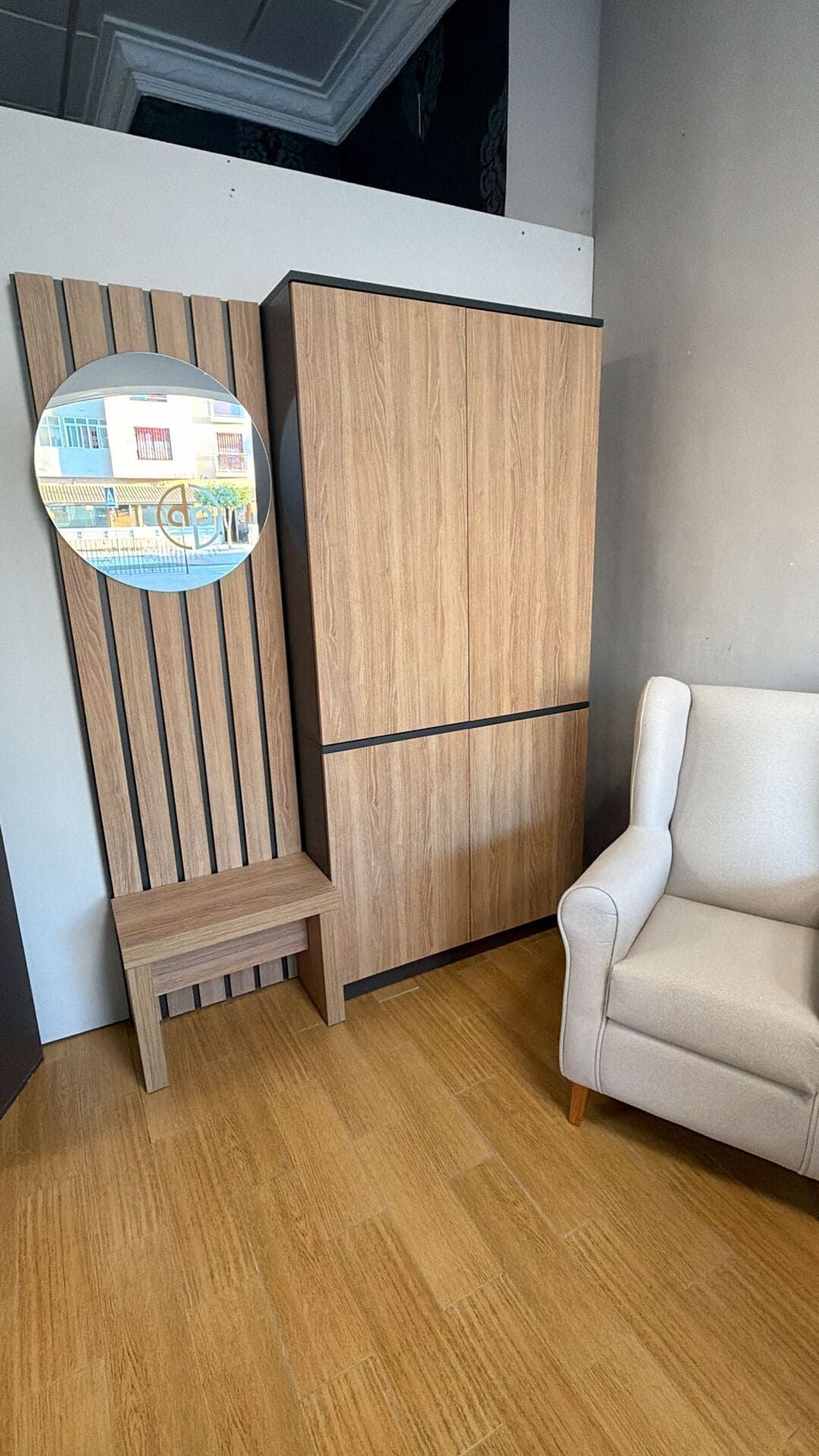 Armario, silla, taburete y panel de pared de madera en una habitación con suelo de madera.