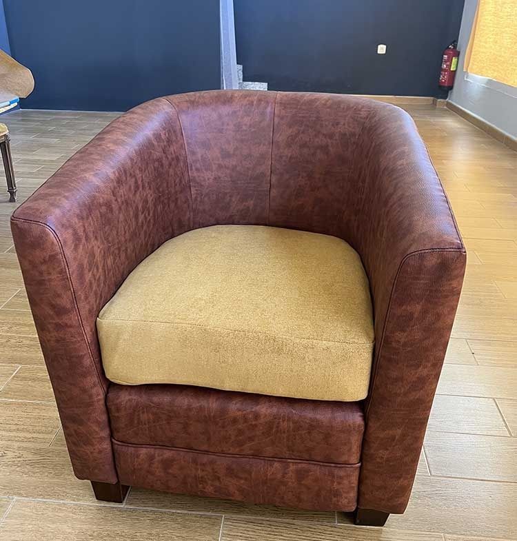 Sillón de cuero marrón con cojín color canela, para interiores.