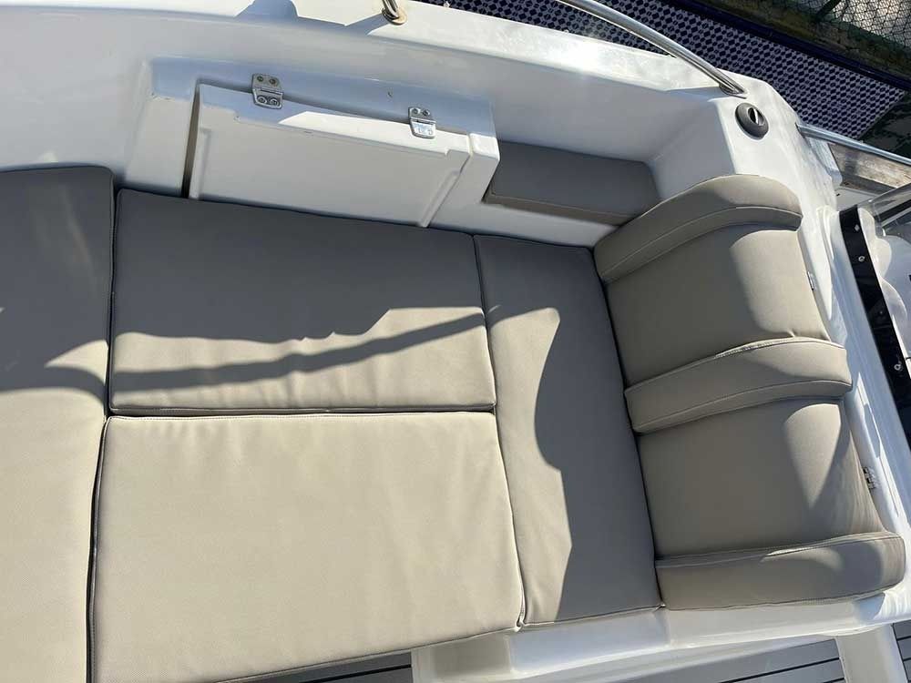 Asientos tipo barco con cojines gris claro y compartimento de almacenamiento blanco.