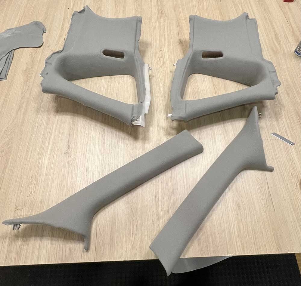 Paneles de plástico gris del interior de un coche dispuestos sobre una superficie de madera.