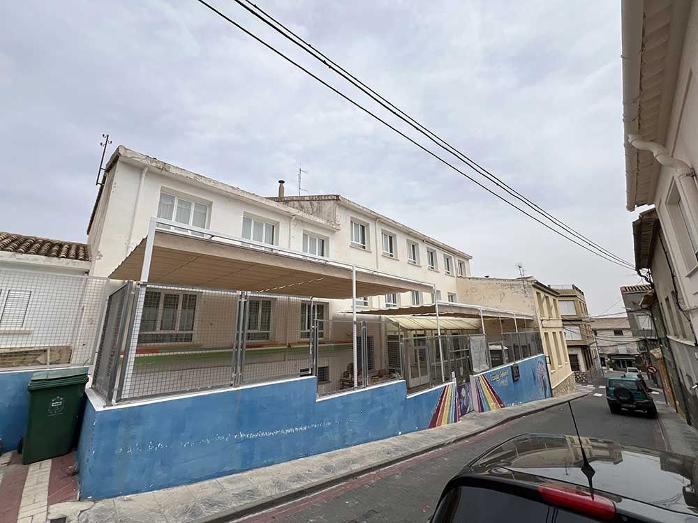 Edificio con pared azul, toldo y vistas a la calle en un día nublado.