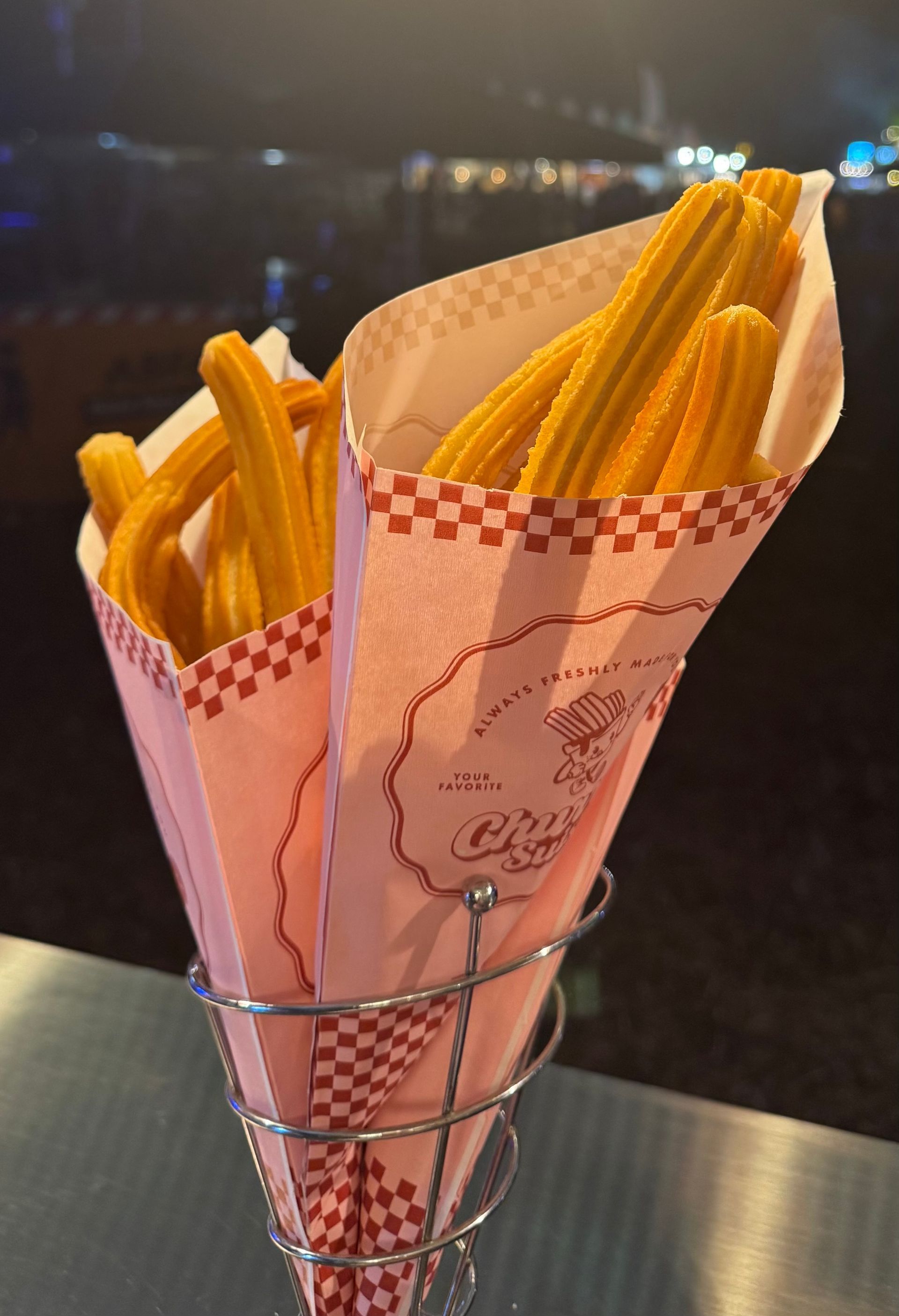 Orangefarbene Churros in Papiertüten an einem Imbissstand