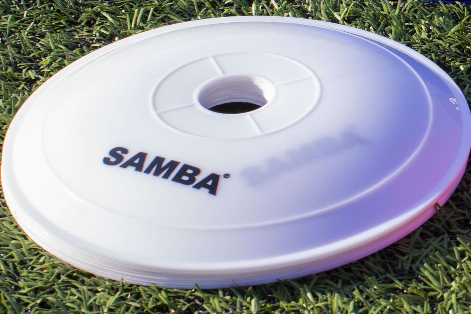 A white samba frisbee is laying on the grass