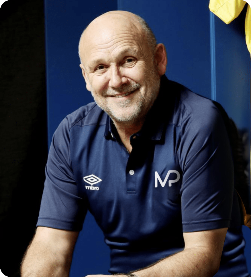 A man wearing a blue umbro shirt smiles for the camera
