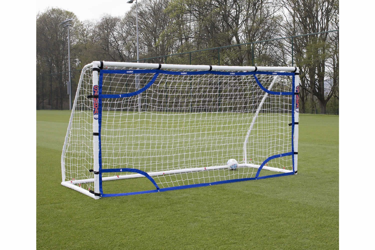 A soccer goal on a field with trees in the background