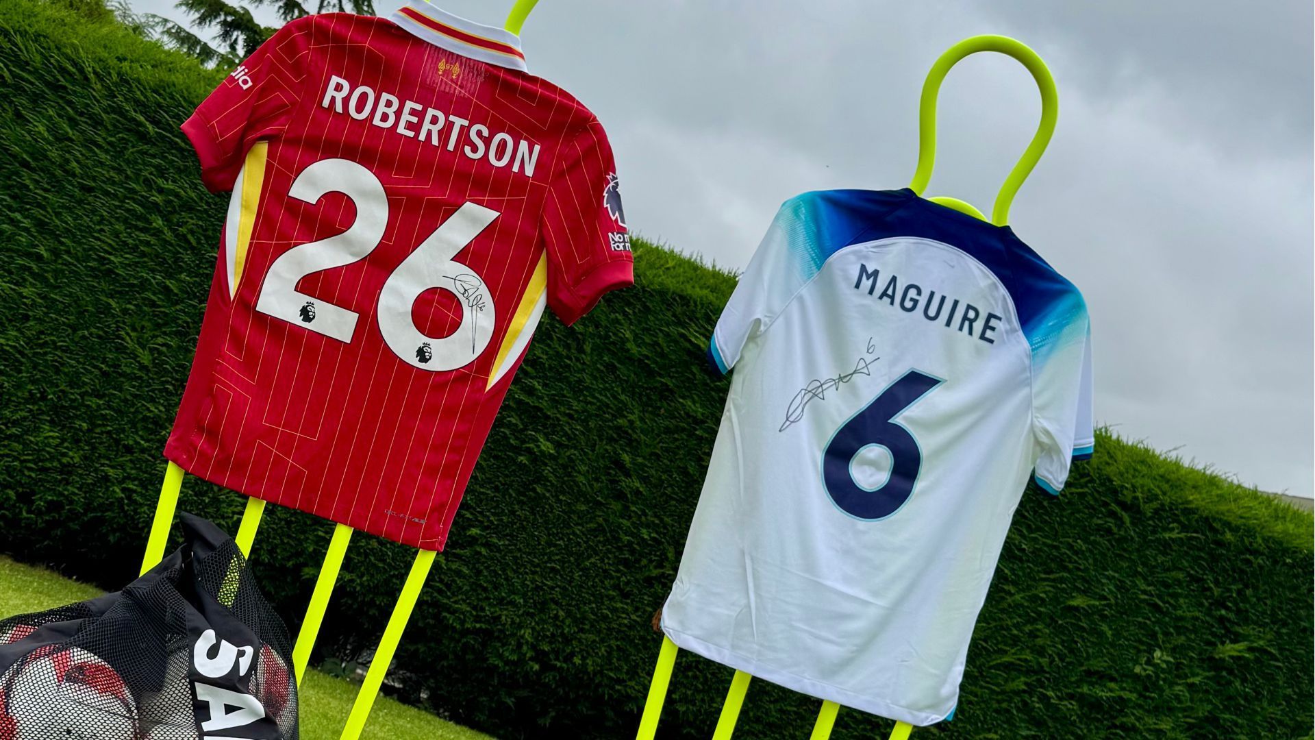 Two jerseys with the names robertson and maguire are hanging on a yellow pole.