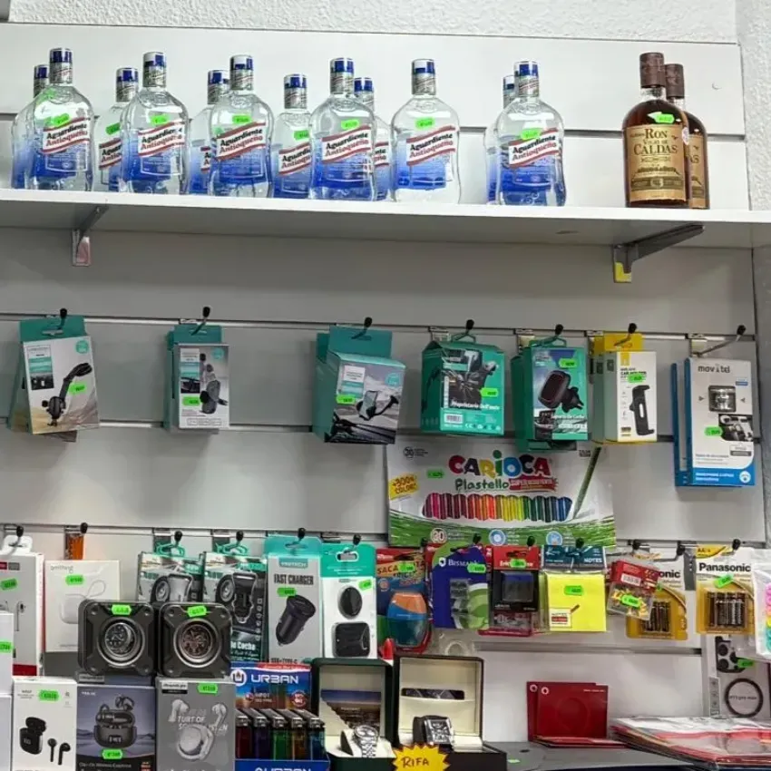 Estantería con bebidas embotelladas y accesorios electrónicos variados en cajas.