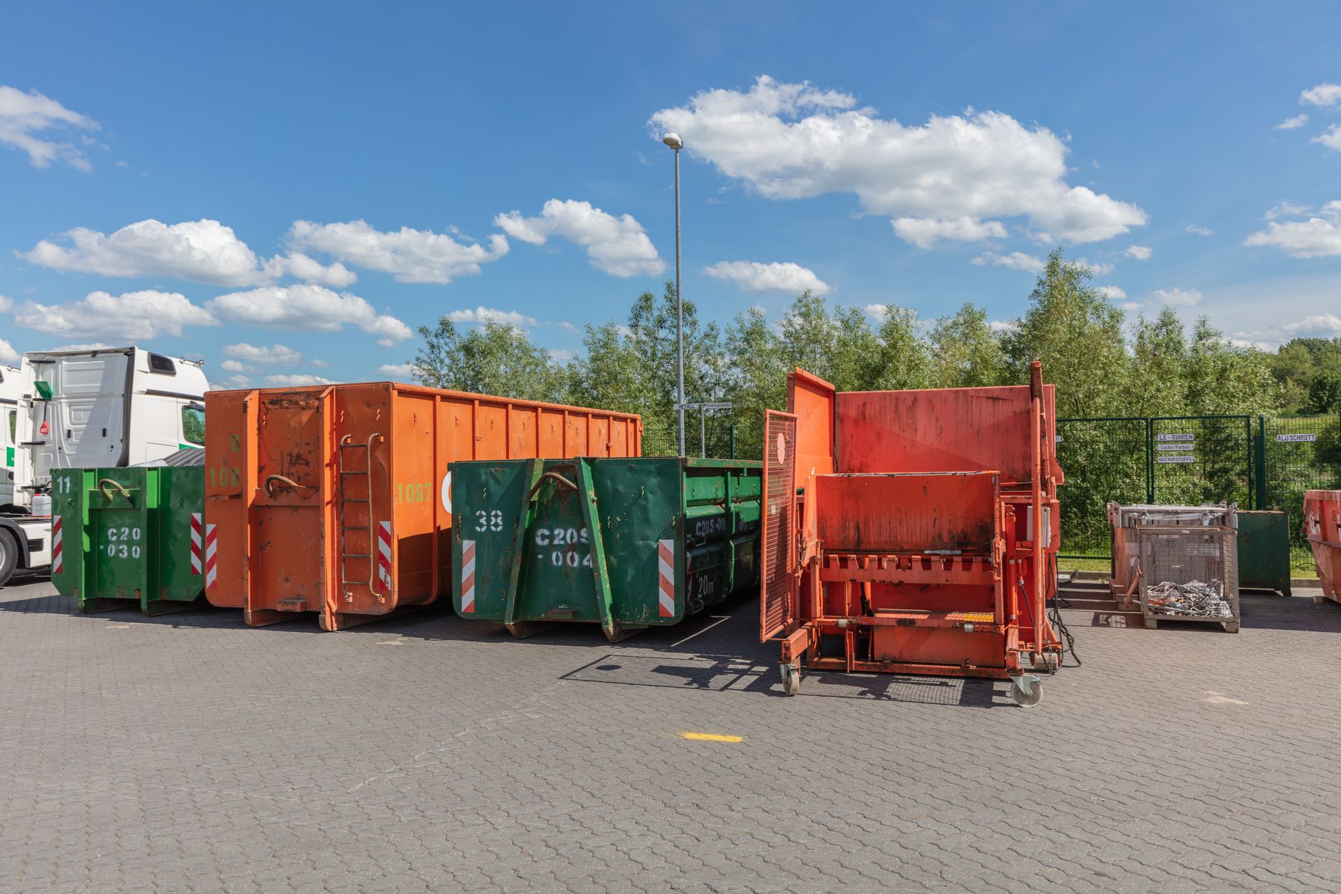 eine Reihe von grünen und orangefarbenen Müllbehältern