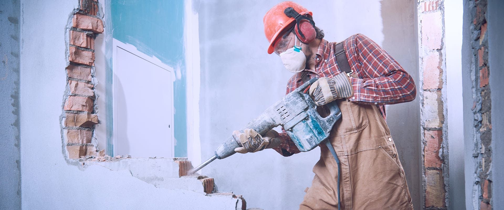 ein Mann arbeitet mit einem Hammer an einer Wand