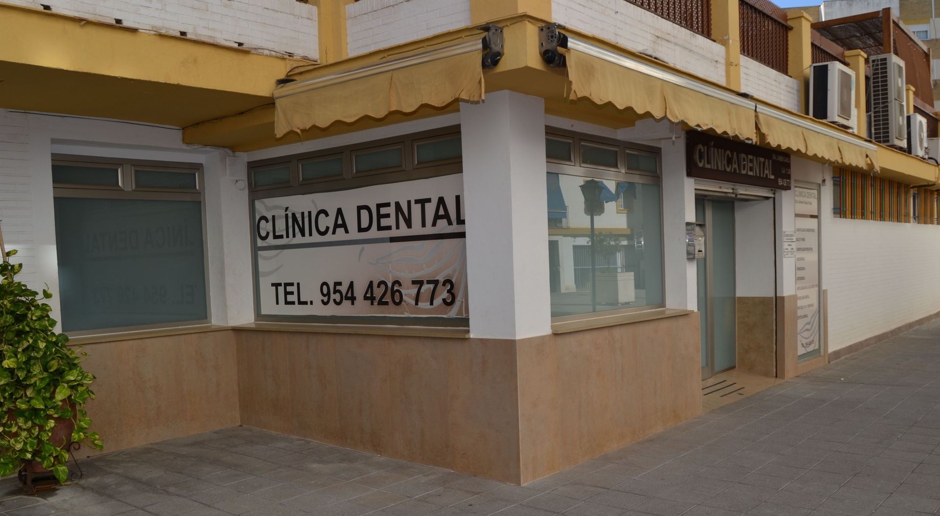 Exterior de una clínica dental. Edificio blanco y tostado con letrero 
