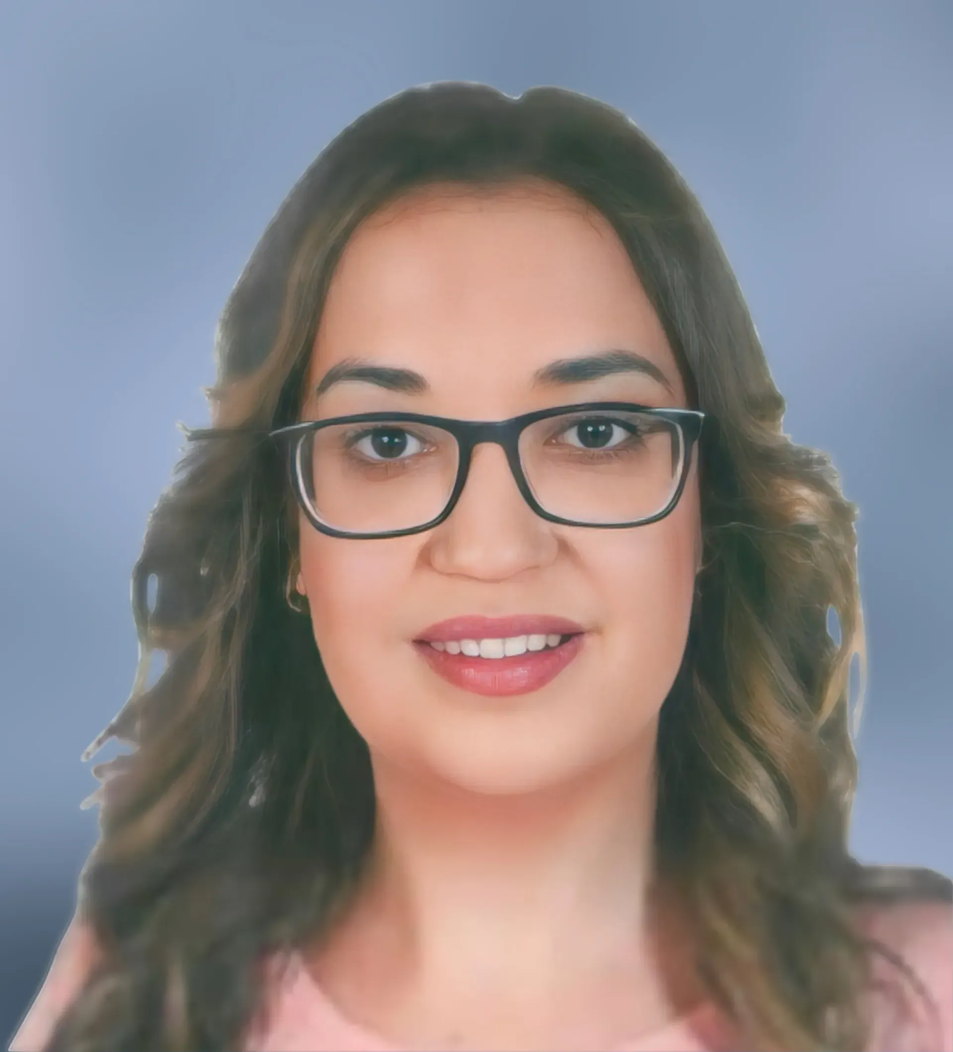 Una mujer con gafas sonríe, tiene el pelo largo y castaño y viste una blusa rosa sobre un fondo degradado azul.