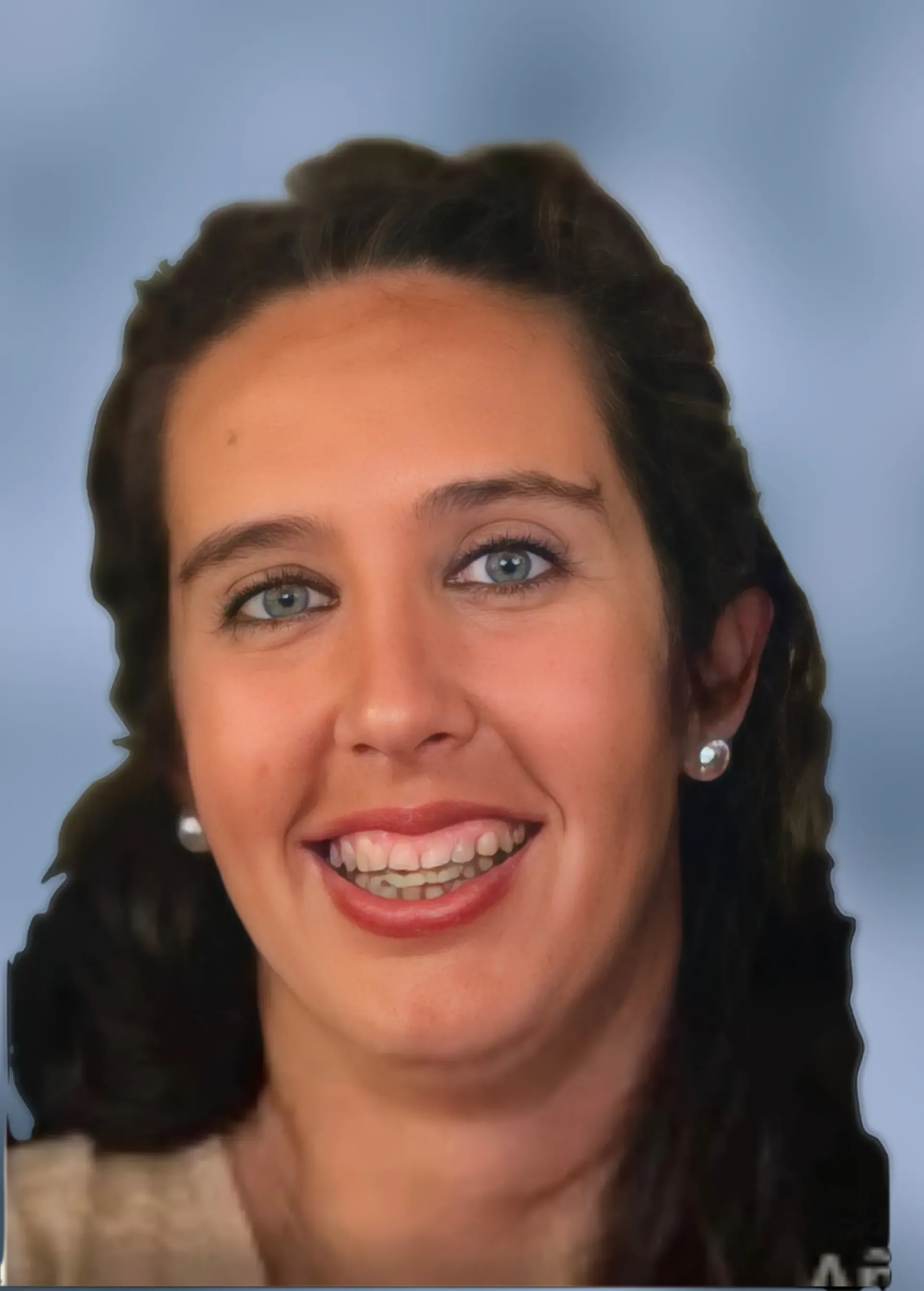 Una mujer con ortodoncia sonríe al espectador, con pendientes de perla y una camisa color canela. Sobre un fondo azul borroso.