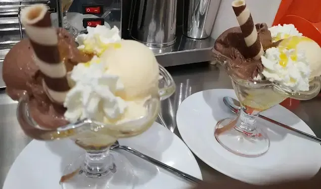 Dos tazones de helado con crema batida y rollitos de oblea de chocolate