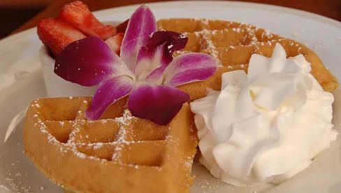 Un gofre con crema batida y fresas en un plato.