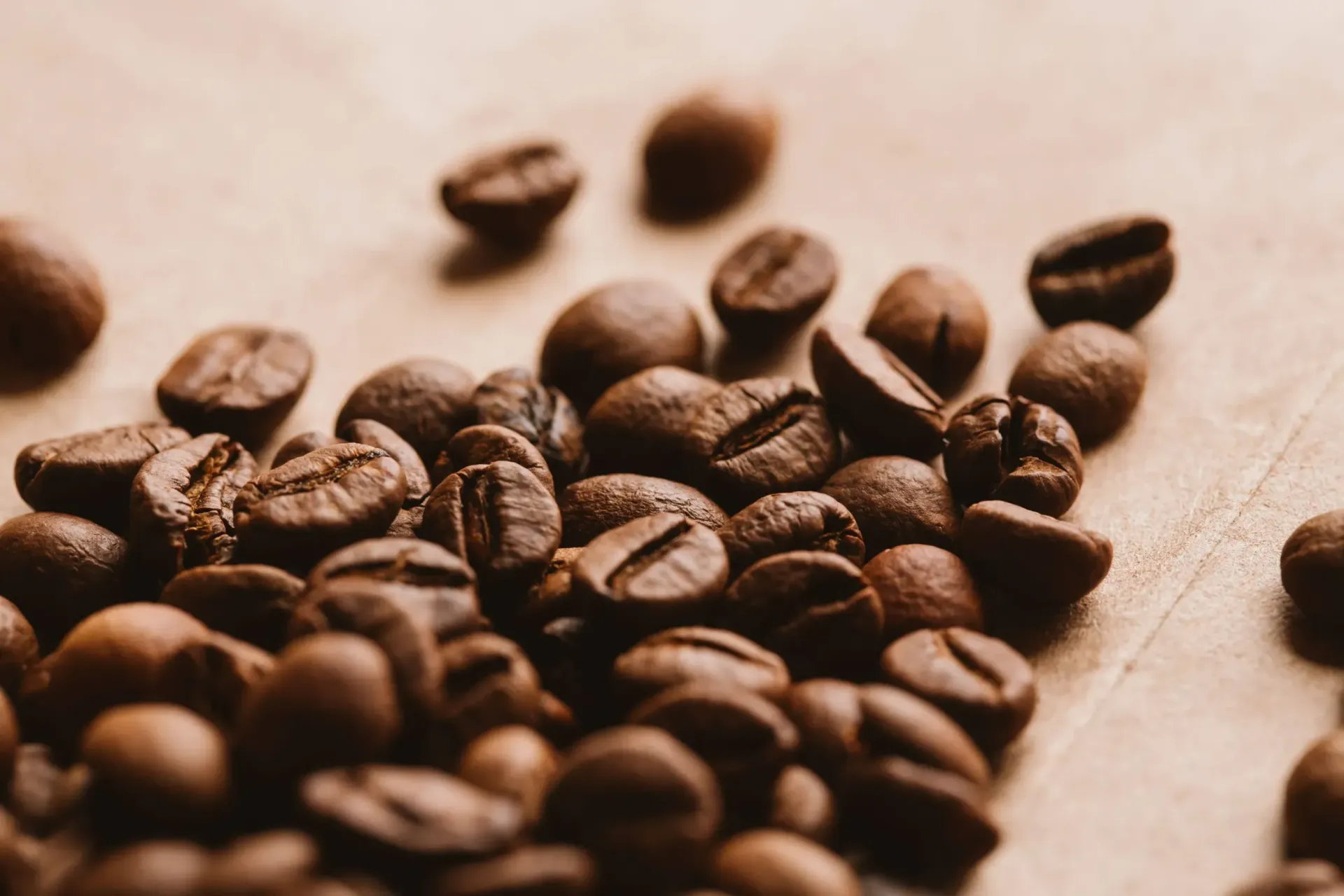 Un montón de granos de café sobre una mesa de madera.
