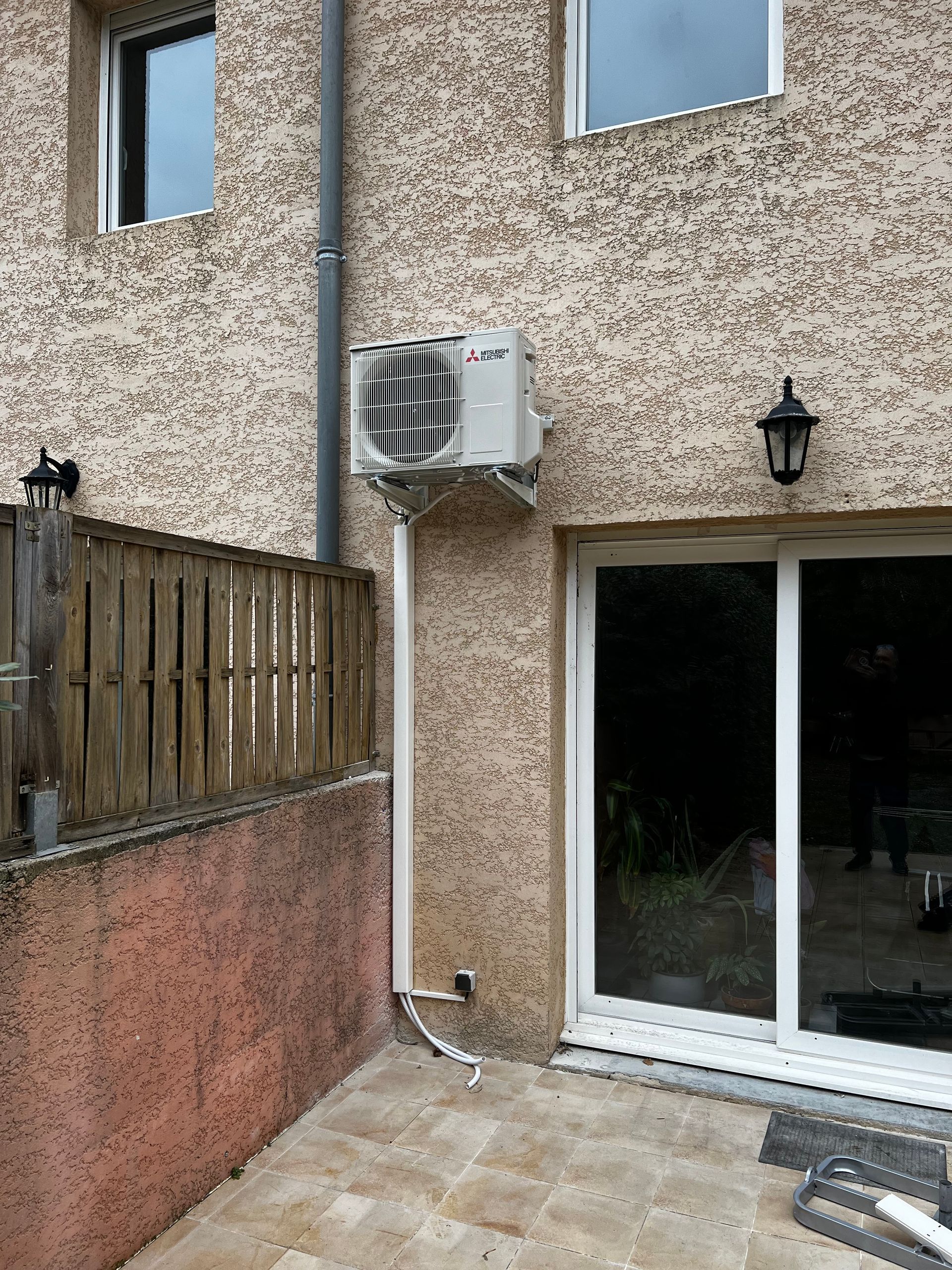 PAC installée en hauteur sur une façade en crépi