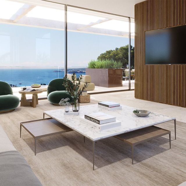 Una sala de estar con una mesa de centro de mármol y un televisor de pantalla plana.