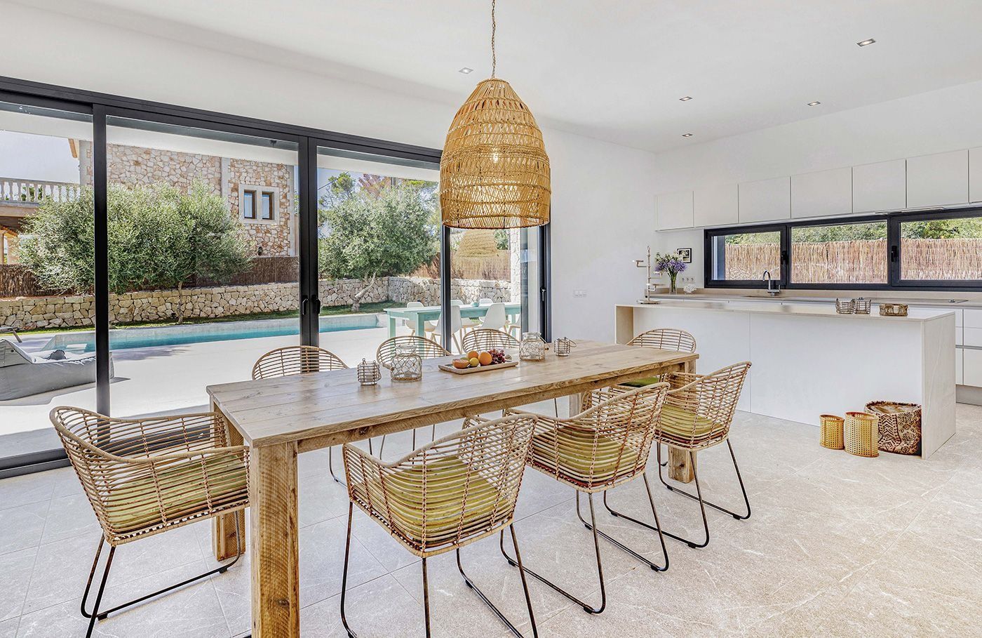 Un comedor con mesa y sillas y una puerta corrediza de vidrio que conduce a una piscina.