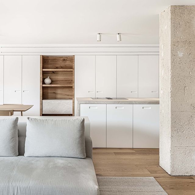Una sala de estar con sofá, mesa y armarios.