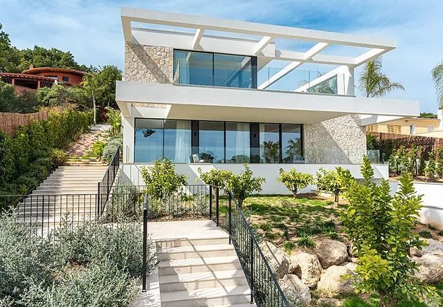 Una casa moderna con muchas ventanas y escaleras que conducen a ella.