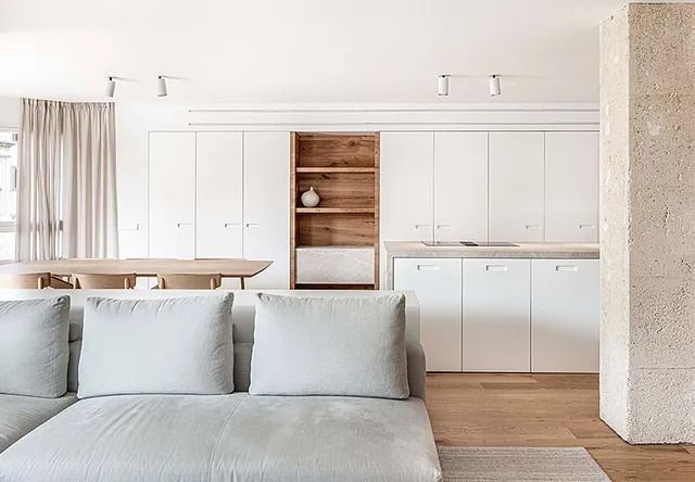 Una sala de estar con un sofá y una cocina al fondo.