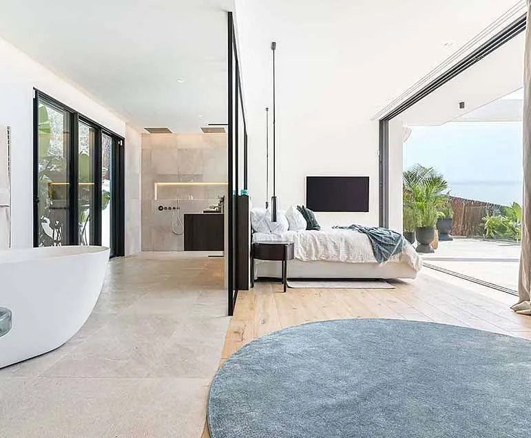 Un dormitorio con una cama grande, bañera, televisión y puertas corredizas de cristal.