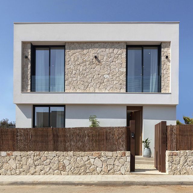 Una casa blanca con una pared de piedra y puertas corredizas de vidrio