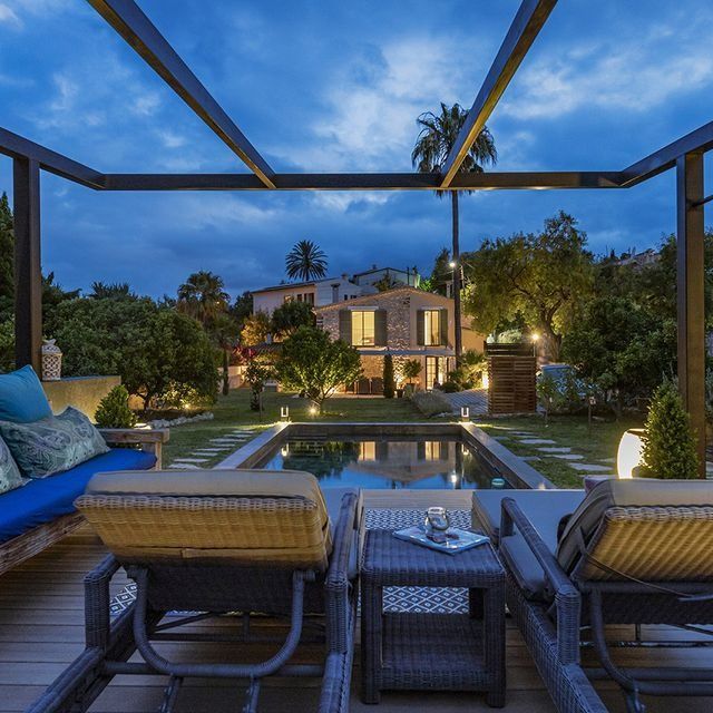 Una vista de una casa desde una terraza con sillas y una mesa.