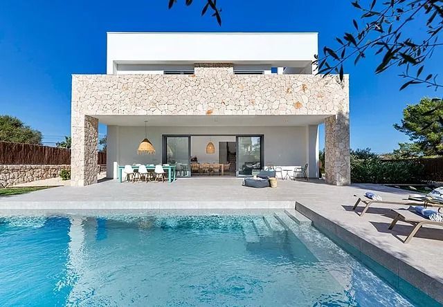 Una gran casa blanca con una piscina delante de ella.