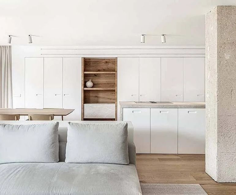 Una sala de estar con un sofá y una cocina al fondo.