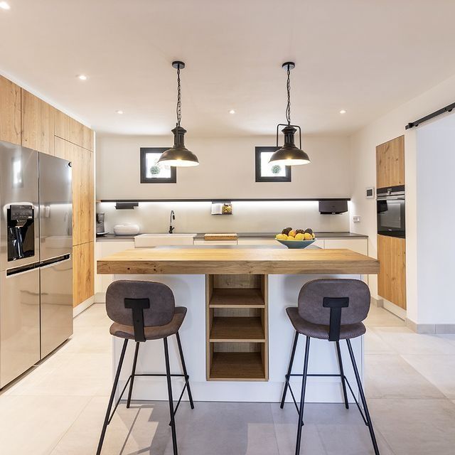 Una cocina con una gran isla y dos taburetes.