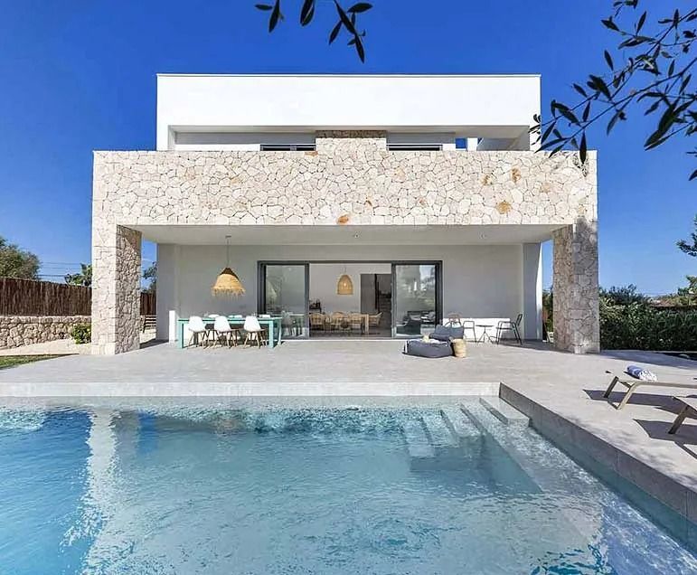 Una gran casa blanca con una piscina delante de ella.