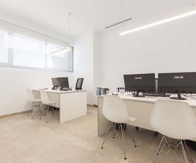 Una habitación con muchos escritorios y sillas con computadoras sobre ellos.