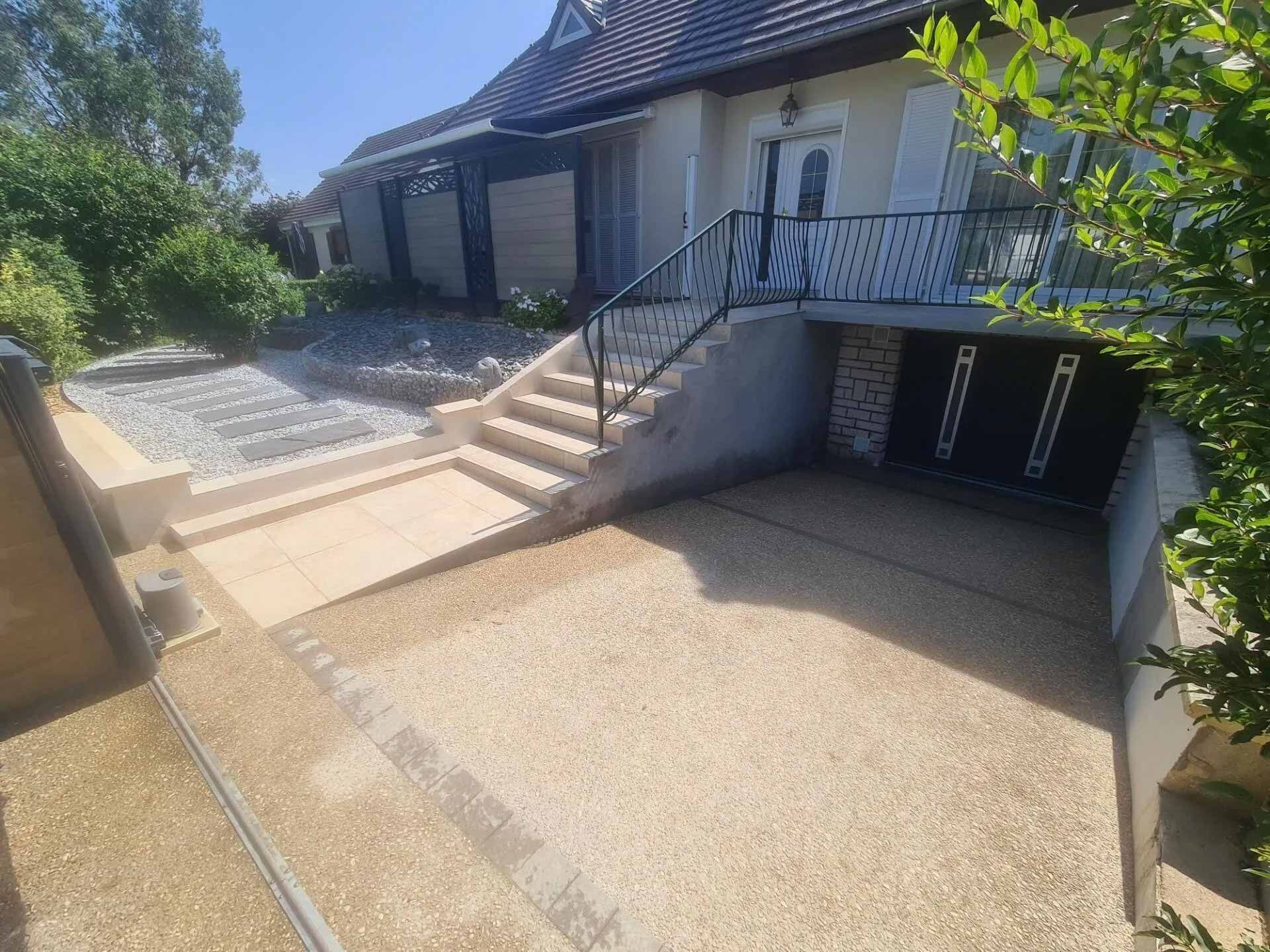 Allée de garage et cour extérieure de maison rénovées.
