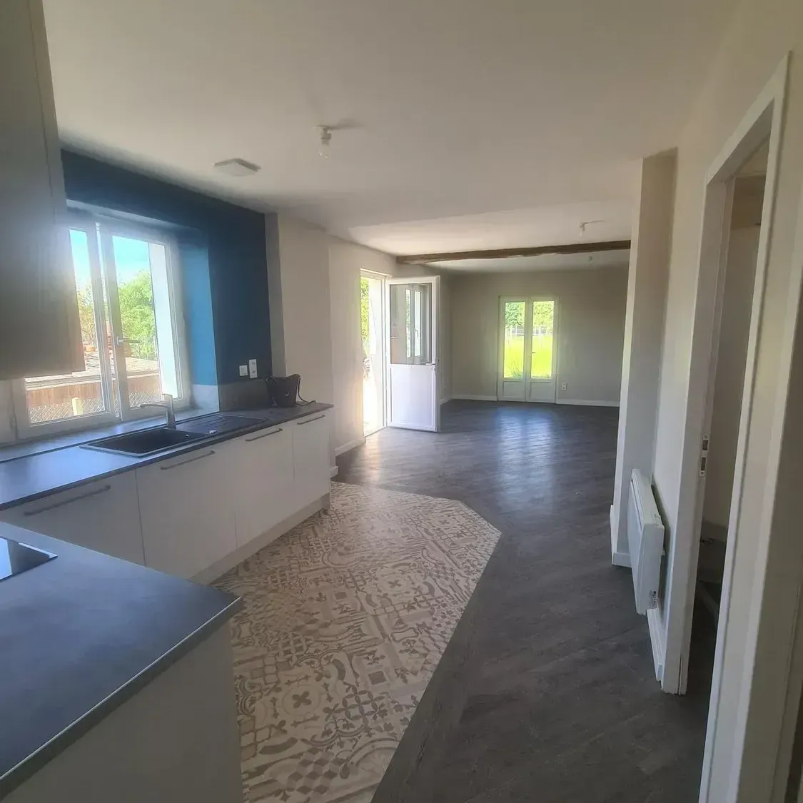 Intérieur de maison avec cuisine et salon rénovés.