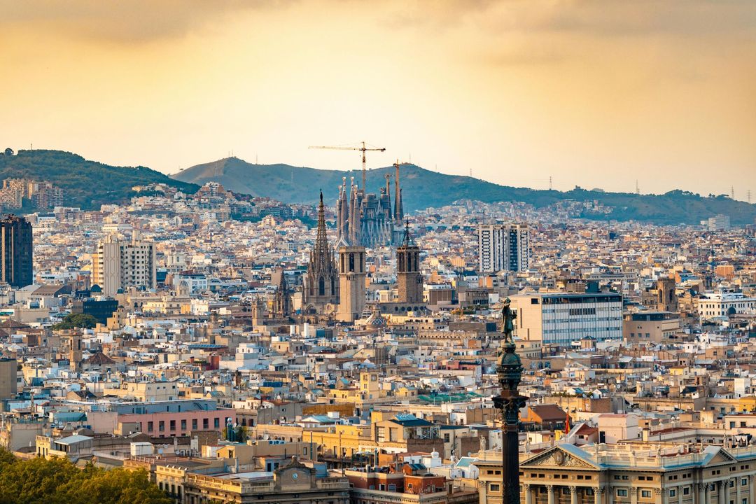 Paisaje urbano de Barcelona con la Sagrada Familia, bajo un cielo cálido.