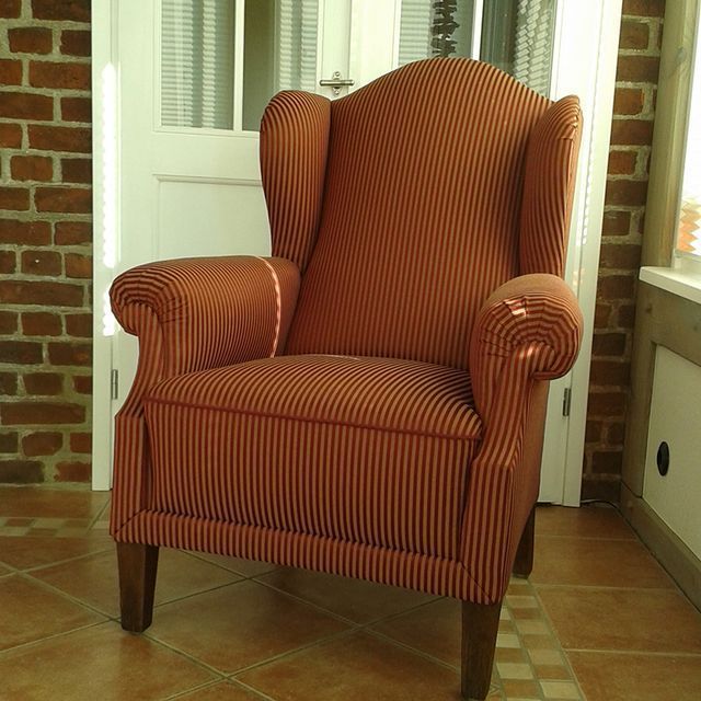 Ein orange gestreifter Stuhl steht vor einer Backsteinmauer