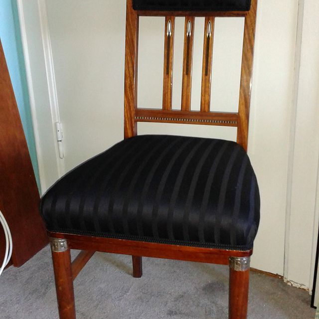 Ein Holzstuhl mit schwarz gestreiftem Sitzkissen