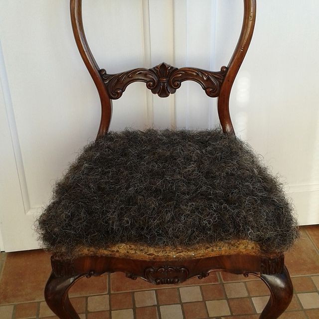 Ein Stuhl mit einem grauen Kissen steht auf einem gefliesten Boden