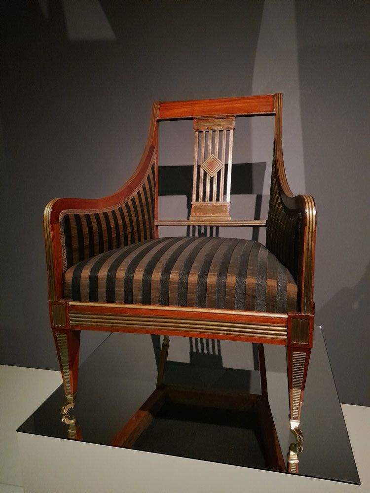 Ein Holzstuhl mit schwarz-gold gestreifter Sitzfläche