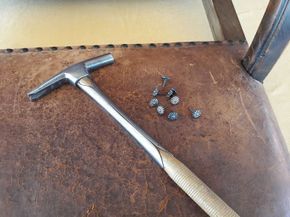 Auf einem braunen Ledersessel liegt ein Hammer.