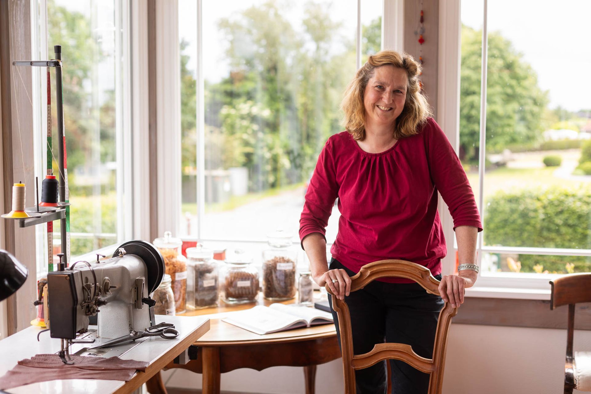 Eine Frau lehnt auf einem Stuhl vor einer Nähmaschine.